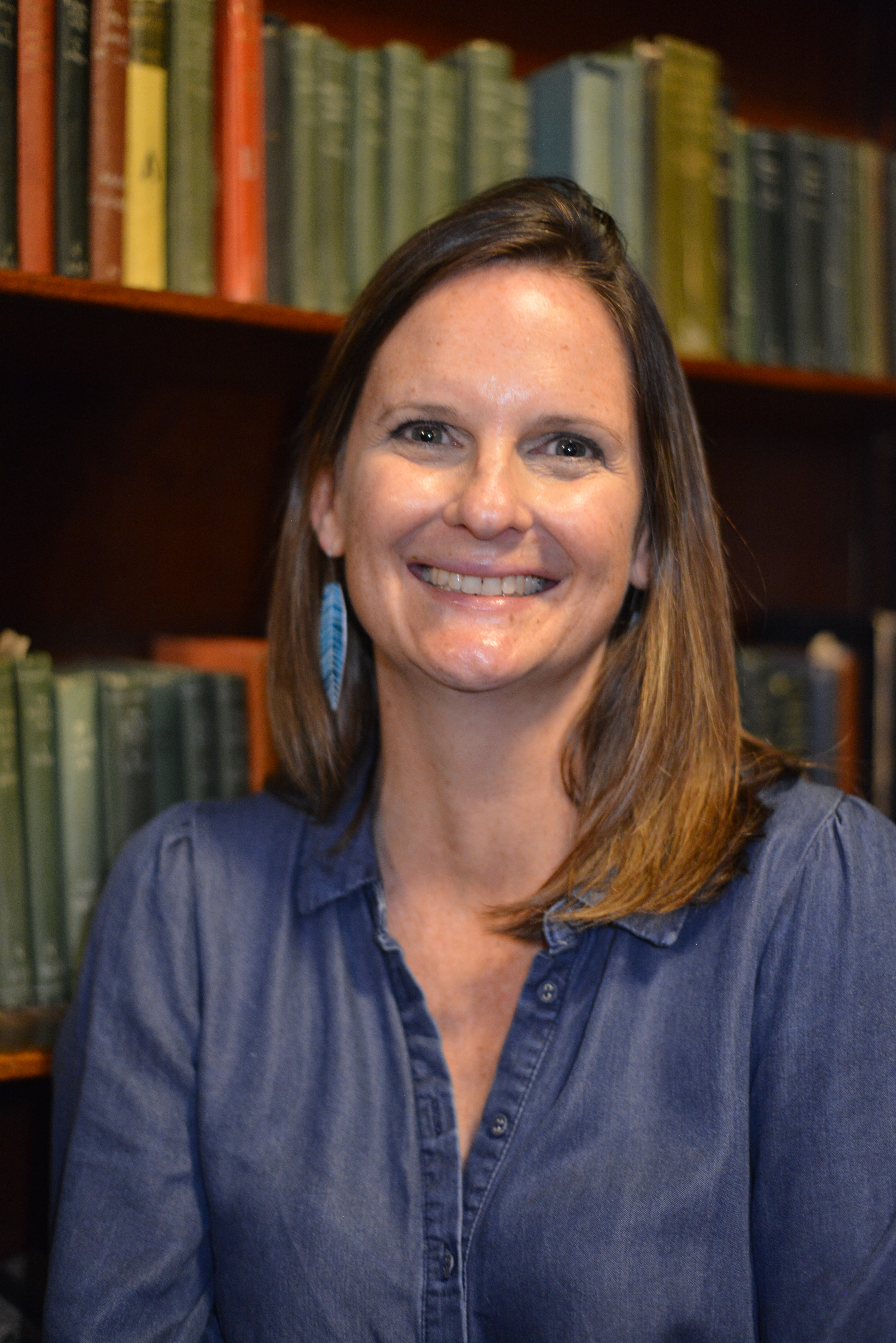 Rebecca Dowd smiling in front of library shelves.